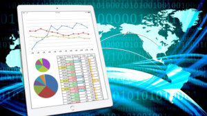 Tablet displaying a line chart, two pie charts, and a data table against a blue digital world map background.