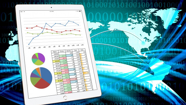 Tablet displaying a line chart, two pie charts, and a data table against a blue digital world map background.